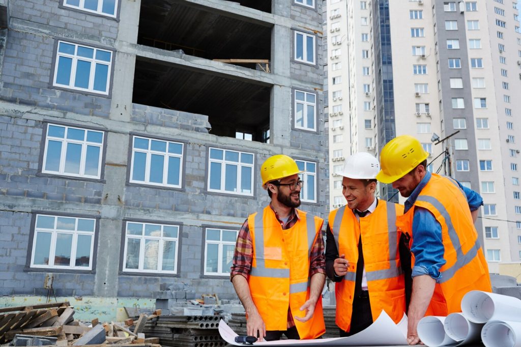 Construction team reviewing plans at a high-rise building site.
