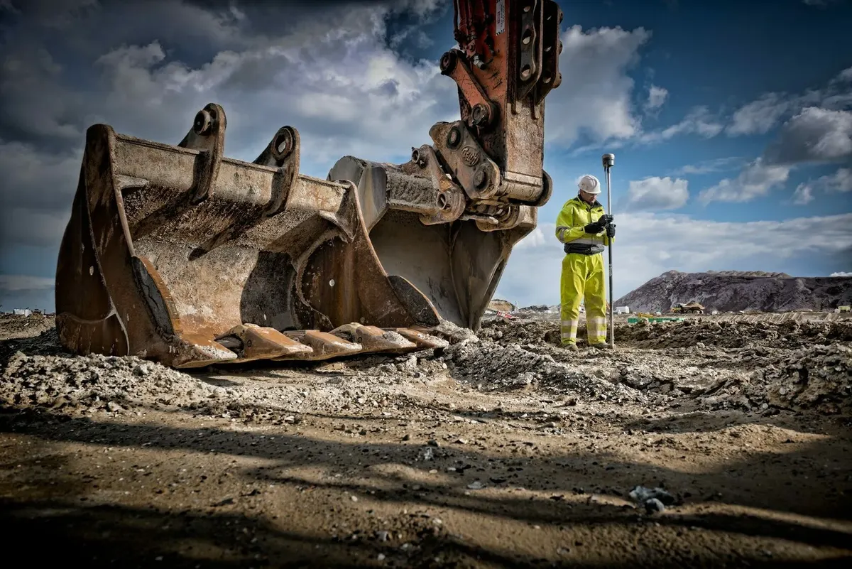 Site surveyor next to an excavator on a UK construction site