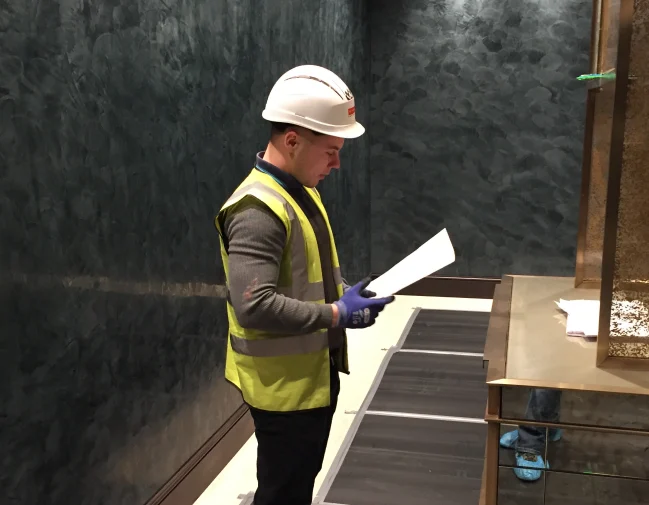 Site manager in a hard hat checking drawings on a fit-out
