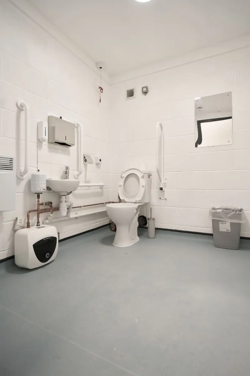 Accessible WC with grab rails and a white resin floor