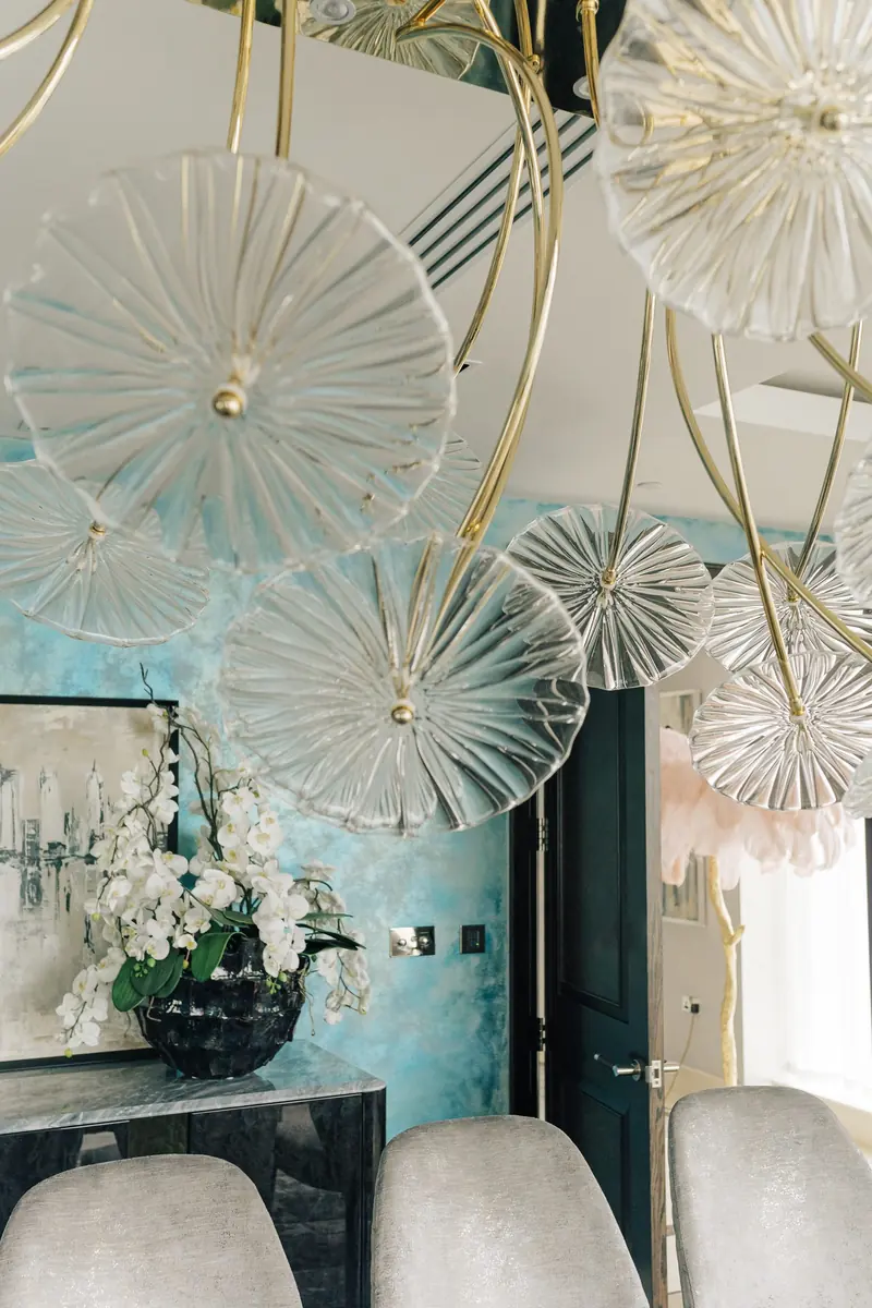 Dining area with a glass flower chandelier and polished plaster walls
