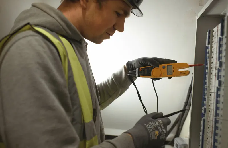 Electrician testing a distribution board with a voltage tester