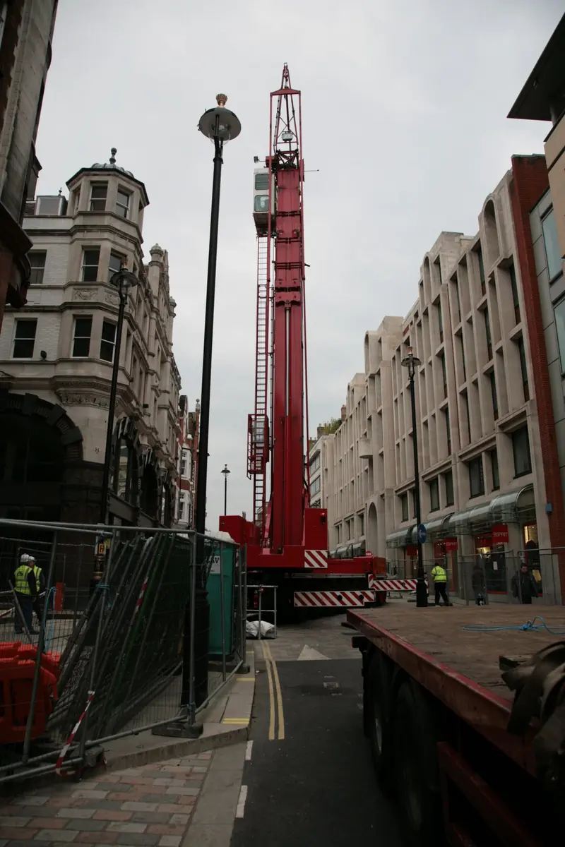 London street with a mobile crane and hoarding beside a building