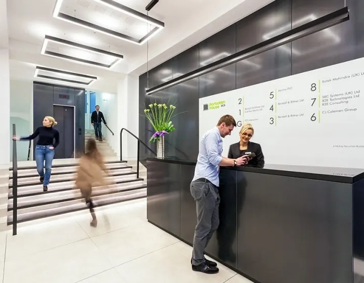 Office reception with people at the desk and on the stairs