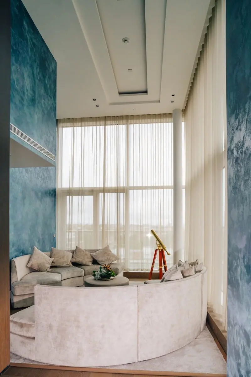 Penthouse lounge with a curved sofa and full-height curtains