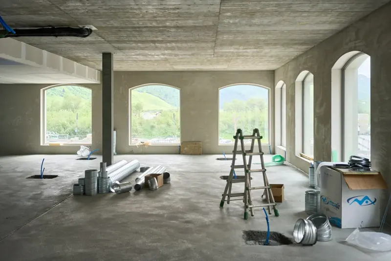 Open-plan room mid fit-out with ductwork and a ladder on the floor