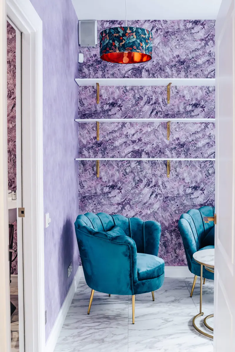 Salon treatment room with purple textured walls and velvet chairs