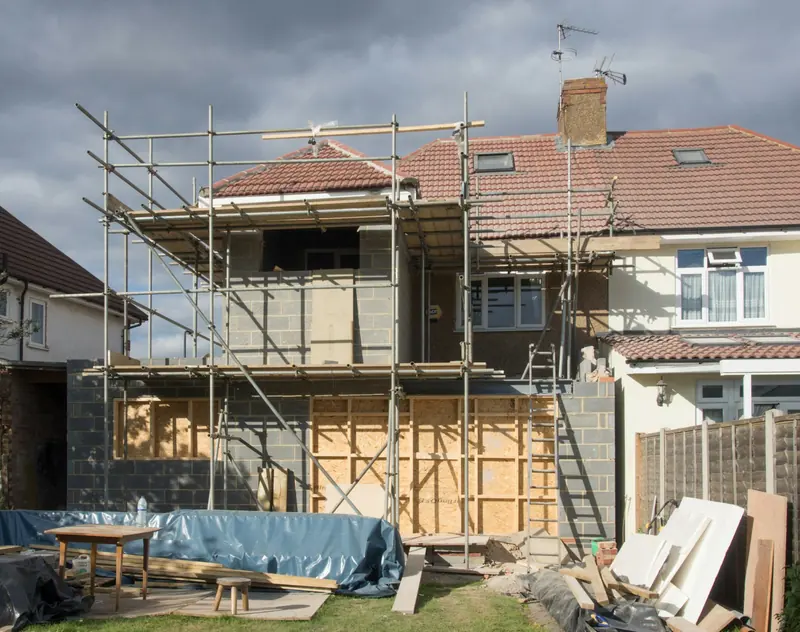 Blockwork rear extension with boarded openings and scaffold