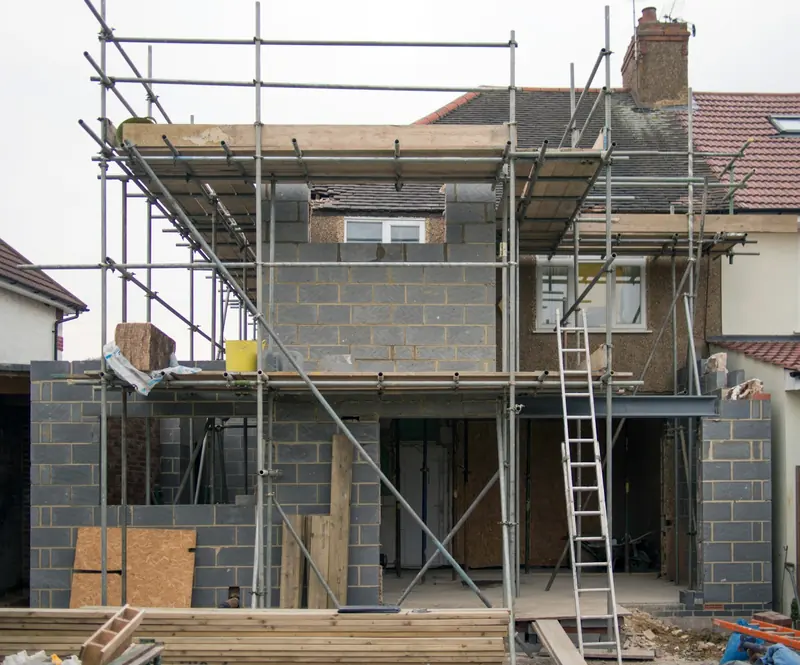 Blockwork shell of a two-storey rear extension with ladders and scaffold