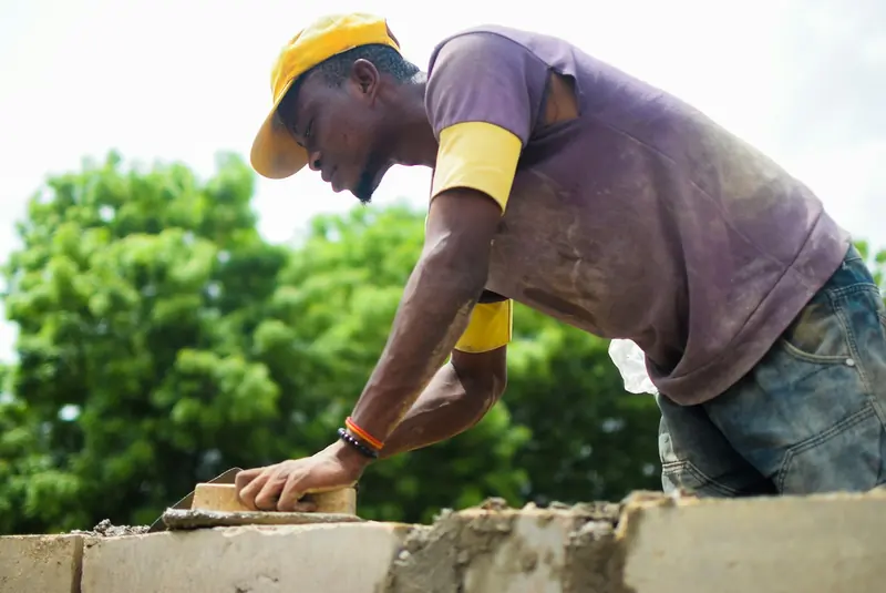Builder laying blocks on a rising wall