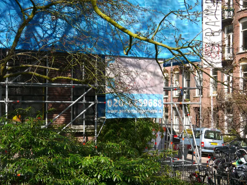 Building behind scaffold and a printed sheet wrap