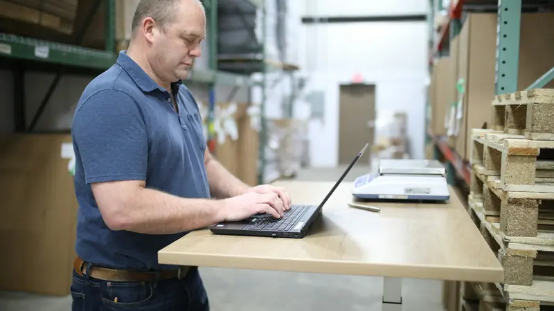 Business owner working at a standing desk in a warehouse