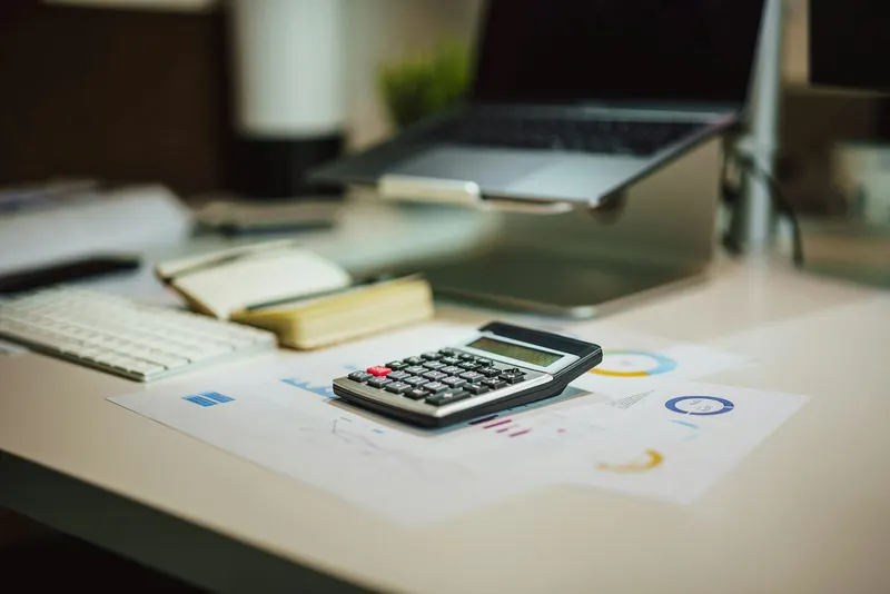 Calculator next to a laptop on a desk