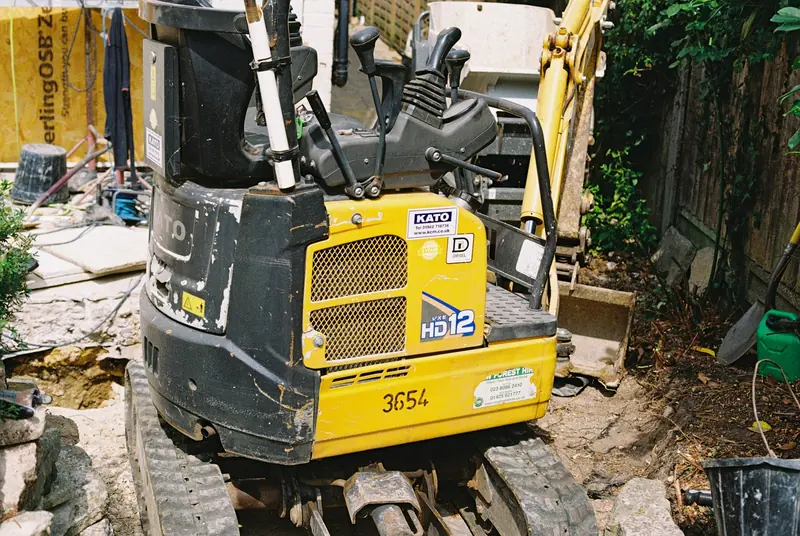 Compact mini digger working in a back garden
