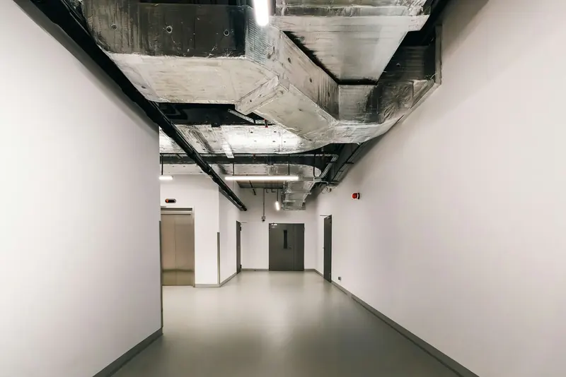 Corridor in a commercial fit-out with exposed ductwork overhead