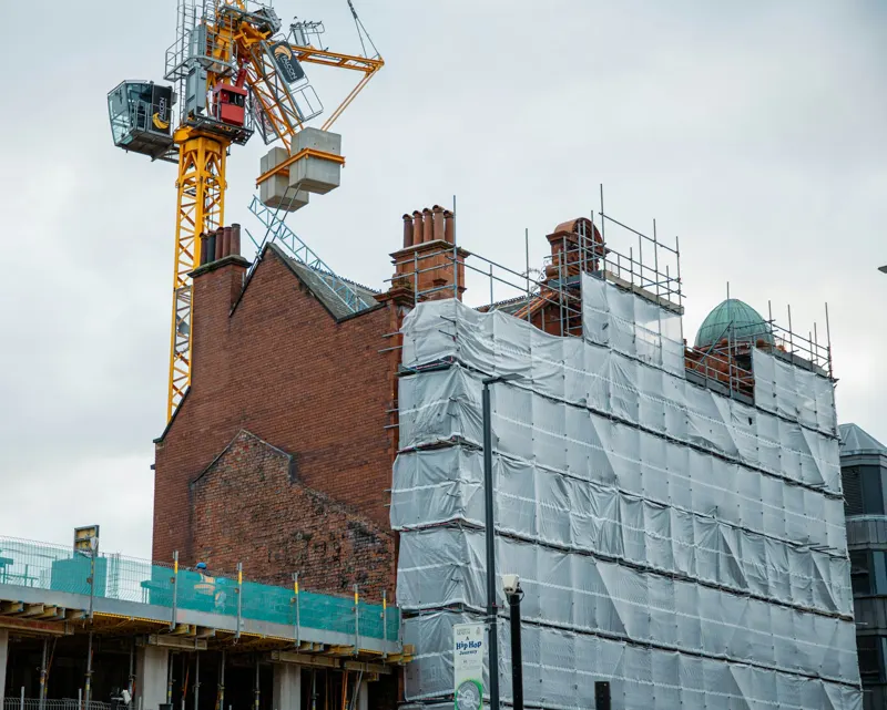 Tower crane over a scaffolded brick building being redeveloped