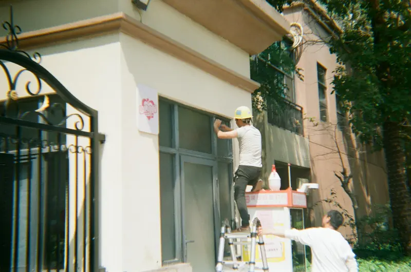 Decorators painting the outside of a house from a stepladder