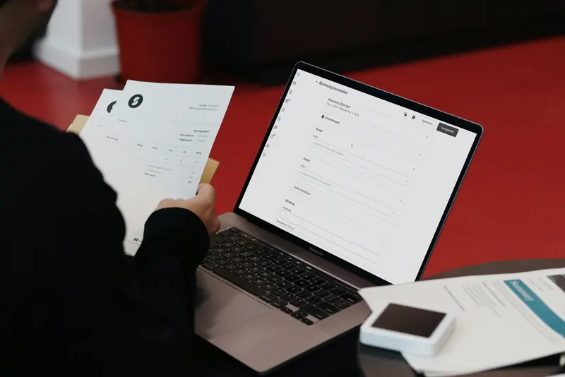 Desk with a laptop and paper invoices