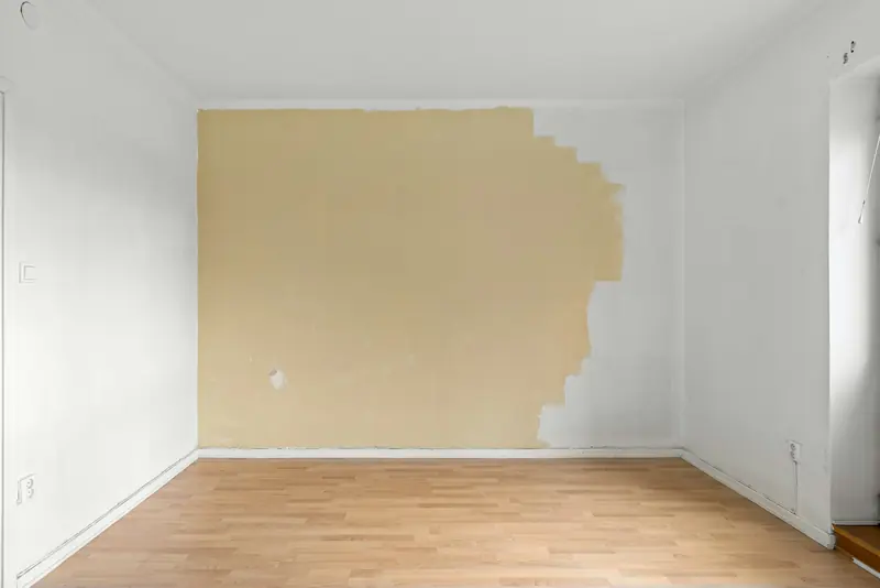 Empty room with a wall half painted in a new colour