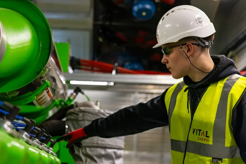 Engineer in hi-vis and a hard hat checking plant room equipment