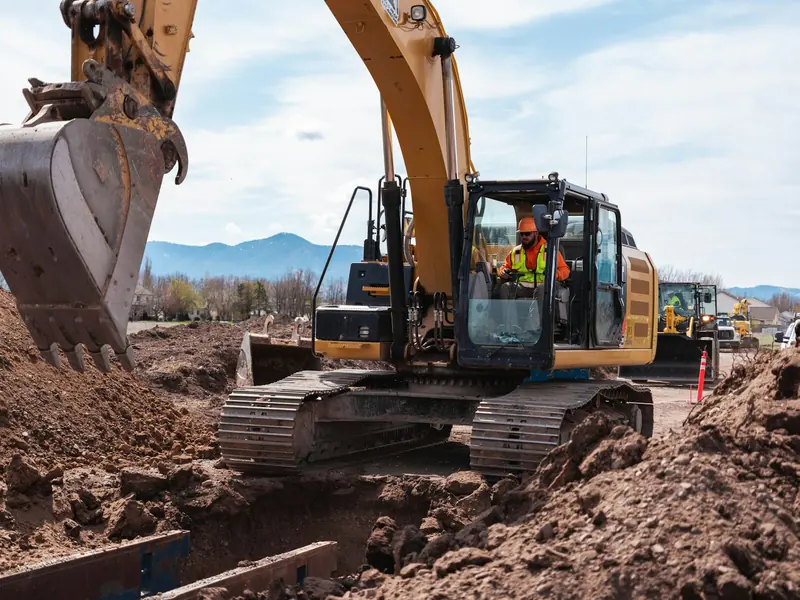 Excavator operator digging a deep trench on site