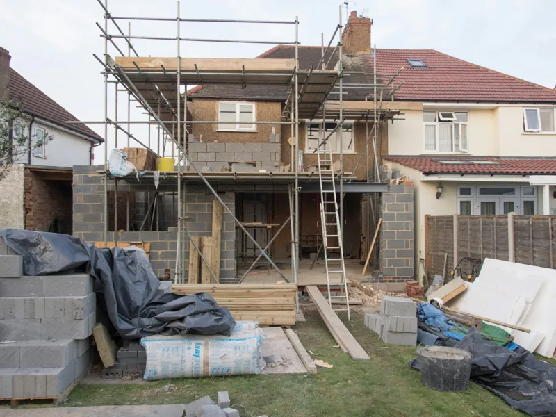 Rear extension in blockwork with steel beams, a ladder and materials on the lawn