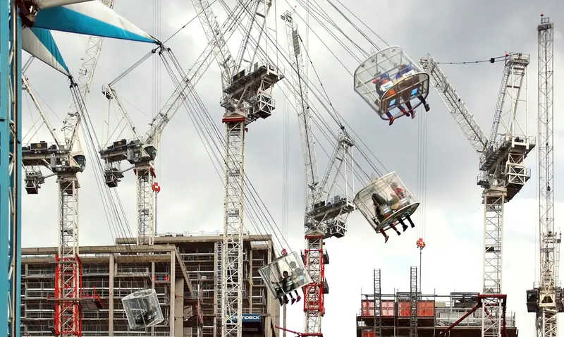 Group of tower cranes over a construction site under a cloudy sky