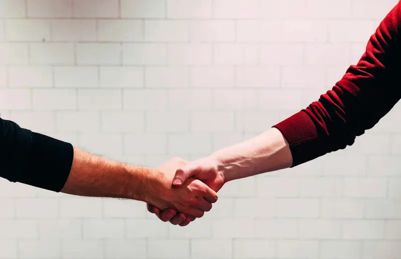 Handshake against a white tiled wall