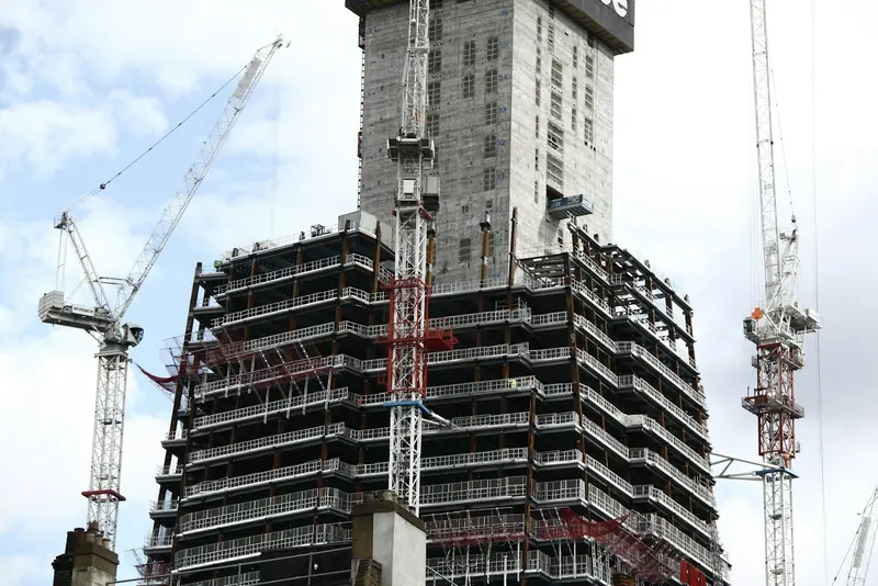 High-rise block under construction surrounded by cranes