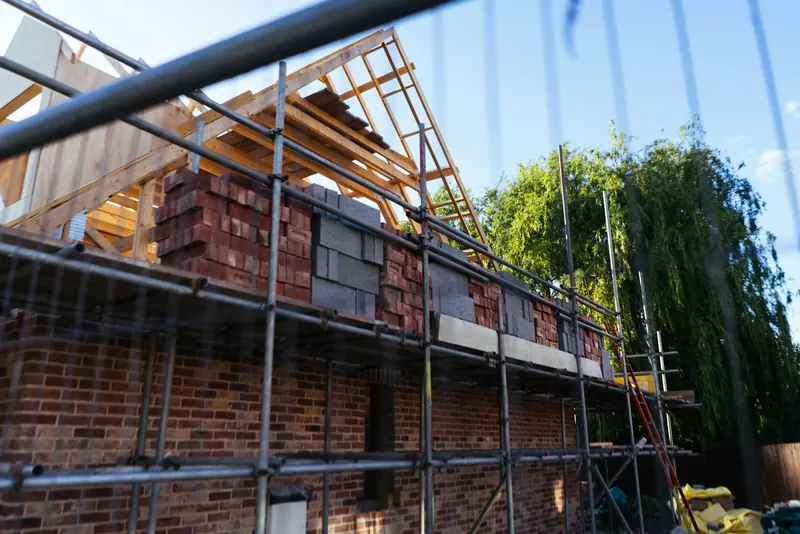 House under construction with scaffold and brick walls