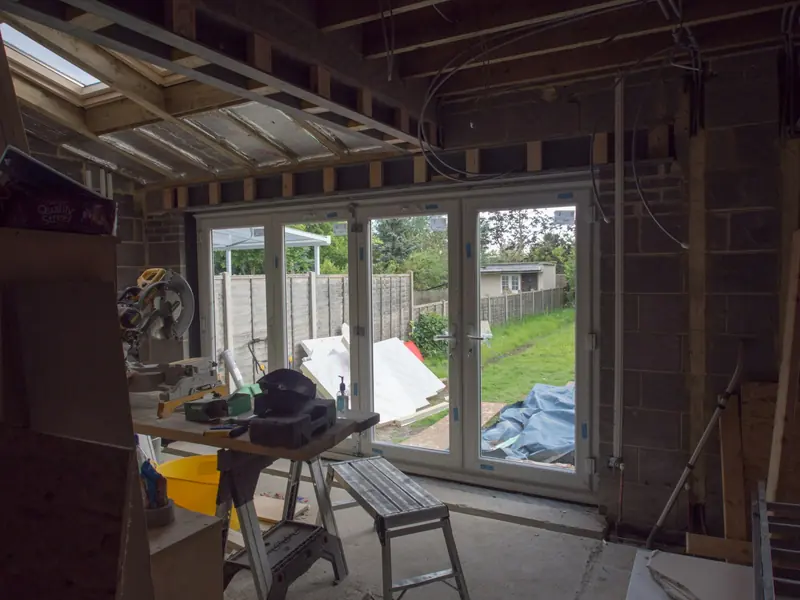 Inside a new extension with bifold doors, joists and a mitre saw