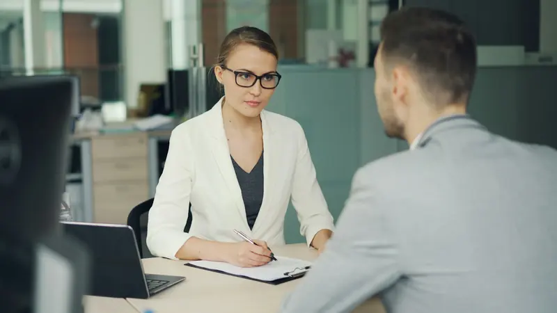 Interviewer taking notes across a desk from a candidate