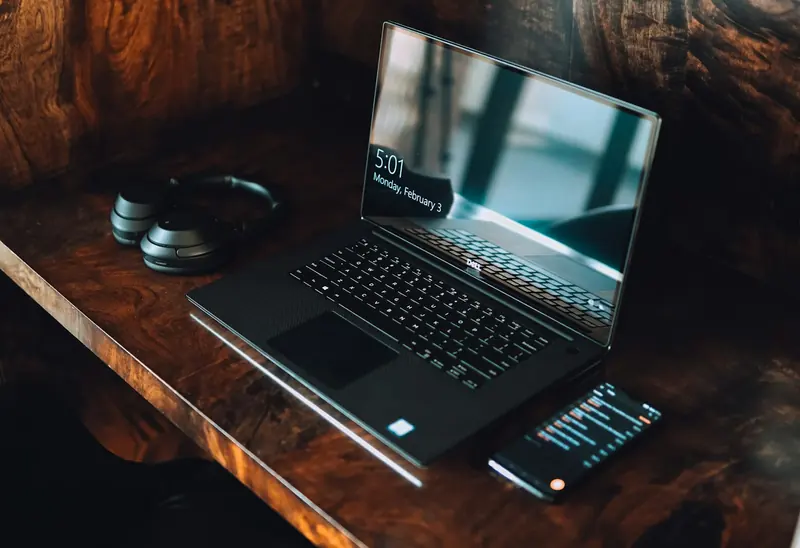 Laptop and phone on a dark wooden desk