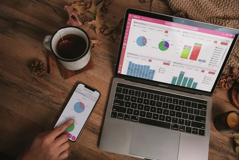 Laptop and phone showing business figures on a desk