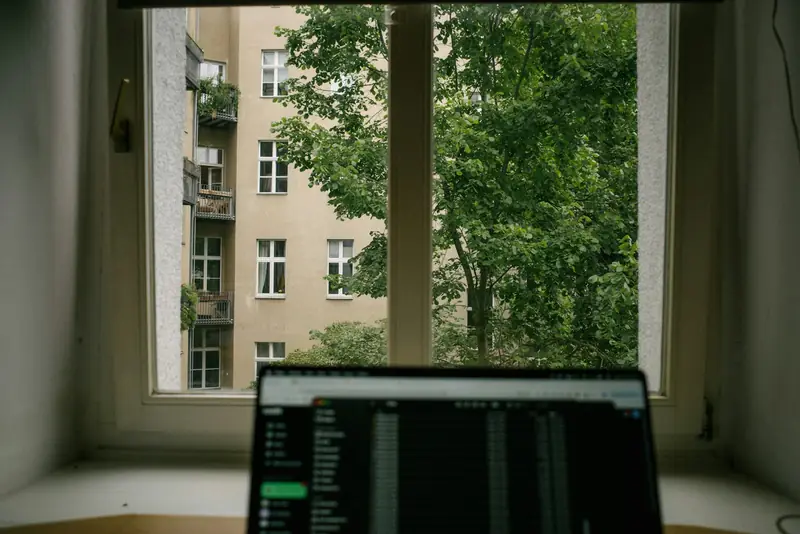 Laptop open on a desk by a window
