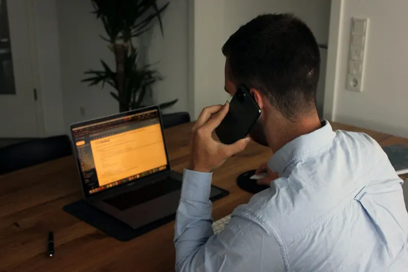 Man on a phone call while working on a laptop