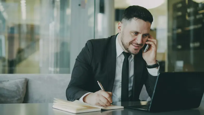 Man on the phone taking notes in a notebook