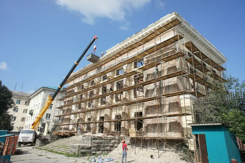 Mid-rise building under scaffold with a mobile crane