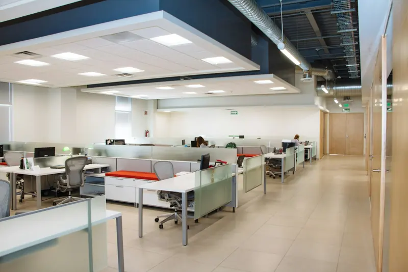 Open-plan office with rows of desks and frosted partitions