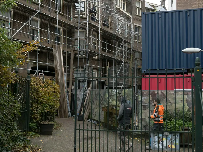 Operative in an orange vest outside a building in scaffold
