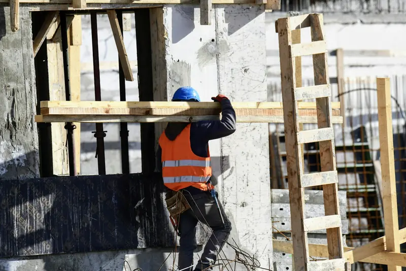 Operative in hi-vis carrying formwork timber on site