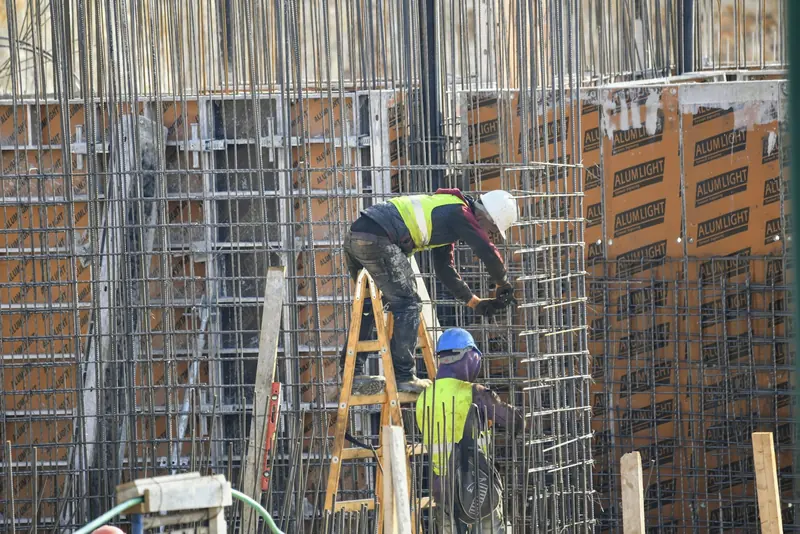Operatives fixing reinforcement cages on a concrete wall