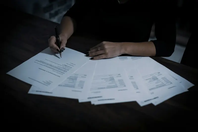 Pages of a contract spread on a table being signed