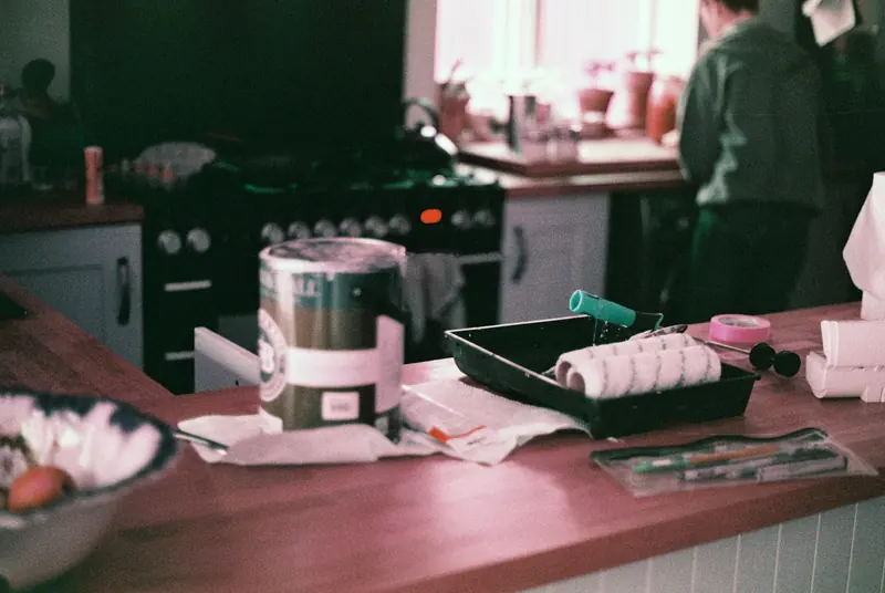 Paint tins, rollers and trays laid out on a kitchen worktop