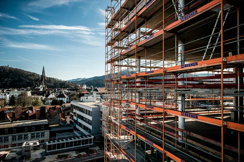 Scaffold on a city building with rooftops in the background
