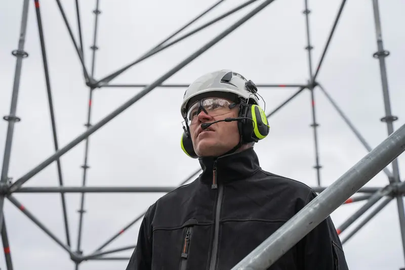 Scaffolder wearing a helmet with ear defenders on a scaffold
