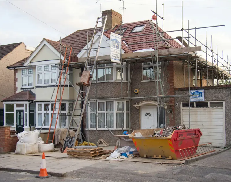 Semi-detached house with scaffold, skip and building materials out front