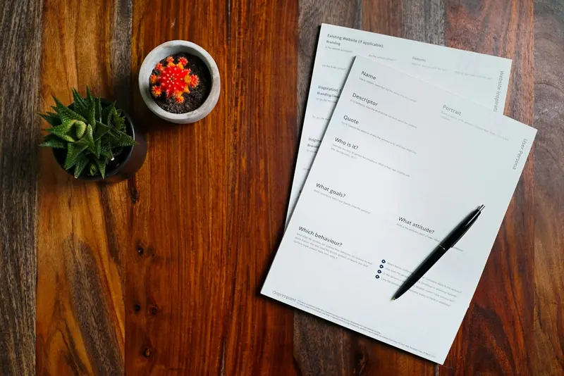 Sheets of paper and a pen on a wooden desk