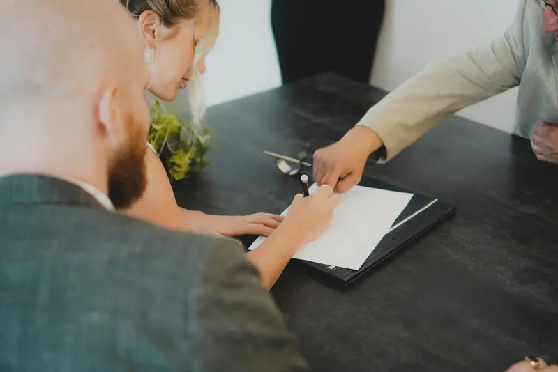 Signing paperwork across a desk in a client meeting
