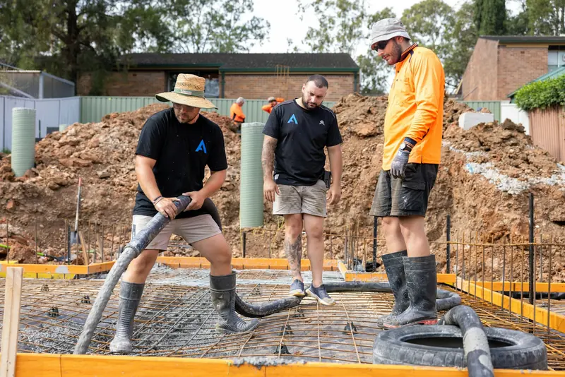 Small crew pouring concrete into foundations on a house plot